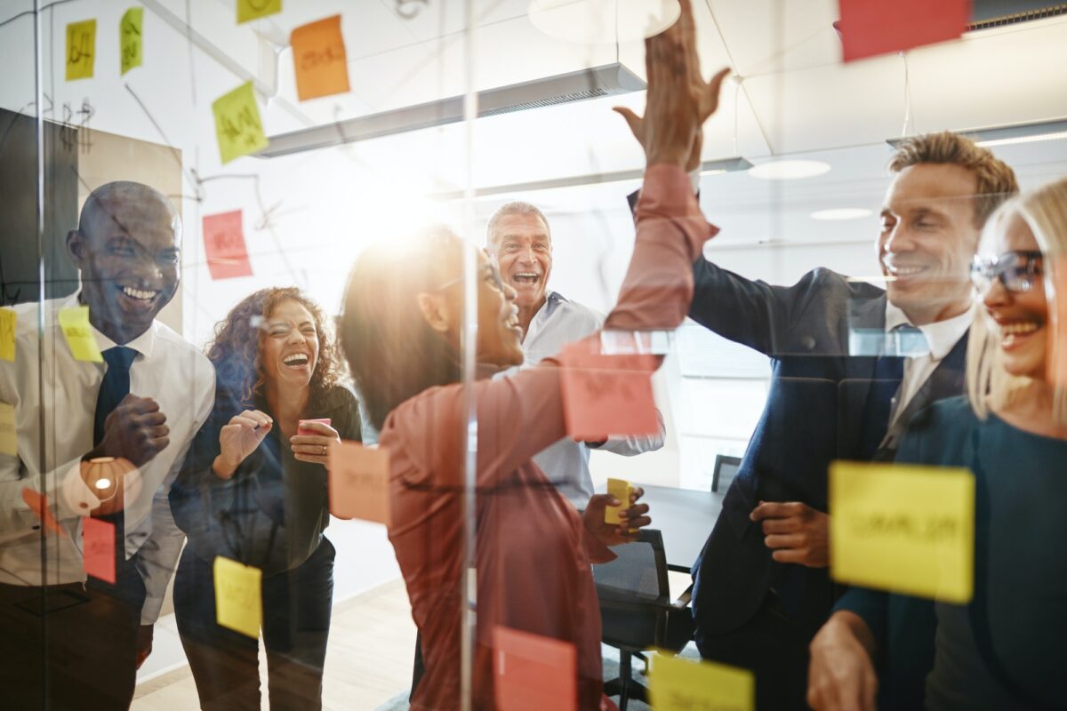 Businesspeople high fiving together with colleagues in an office