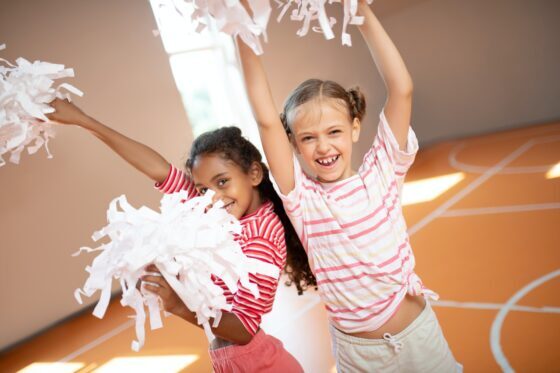 Girls wearing sport clothing laughing while practicing cheerleading