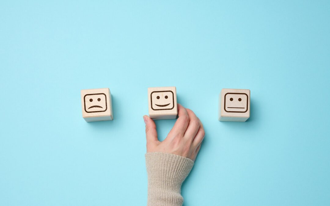 Wooden blocks with different emotions from smile to sadness and a woman's hand